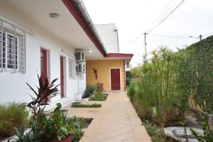Una casa con un camino que conduce a una puerta roja. en Hotel Ophelia Lodge, en Port-Gentil