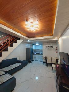 a living room with a blue couch and a ceiling at Cozy Aesthetic 2BR 3 storey Home with Rooftop in San Mateo