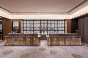 a lobby with benches and a wall of wine bottles at Orange Crystal Qingdao Liaoyang West Road Guoxin Sports Center Hotel in Qingdao