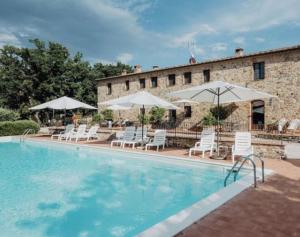 a large swimming pool with white chairs and umbrellas at Una Stanza con vista tra le colline senesi - Friland in Fattoria Falsini