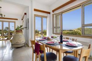 a dining room with a table and chairs and windows at Villa Akamas Bayview by Villa Plus in Lachi