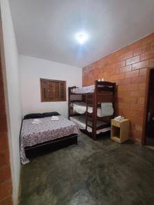 a room with two bunk beds and a brick wall at Chácara La Belle de Jour in Piedade