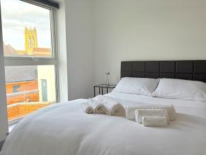 a white bed with towels on it with a window at Modern 2-Bed Apartment in York City Centre - Walk to Shambles and Top Attractions in York +9 photos