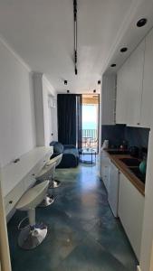 a kitchen with white cabinets and a living room at Bristol in Kvariati