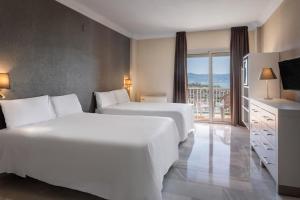 a hotel room with two beds and a balcony at Sol Guadalmar in Málaga