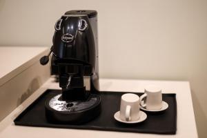 a black coffee maker sitting on a counter with two cups at LUNA Gallery Suites in Naples
