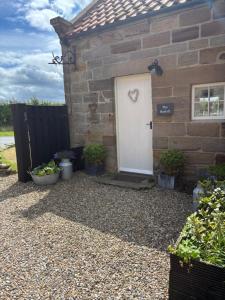 een stenen huis met een witte deur en wat planten bij The Hayloft Cottage in Whitby