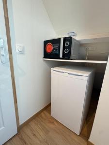 un microondas sentado en un estante sobre una nevera en Royal appart city 5, en Calais