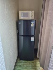 a microwave on top of a refrigerator in a room at Jun House in Jeju