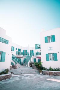 una fila di edifici bianchi con finestre verdi di Celeste Apartments a Ornos