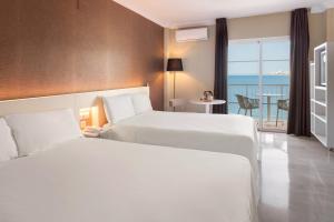 two beds in a hotel room with a view of the ocean at Sol Guadalmar in Málaga