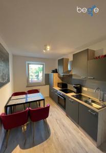 a kitchen with a table and red chairs in it at BEGE APARTMENTS WorkVibe Stay in Duisburg