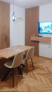 a dining room table with two chairs and a television at Apartments Nada in Budva