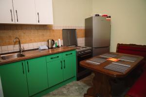 Una cocina con gabinetes verdes, una mesa y un refrigerador. en Villa Morena, en Mostar
