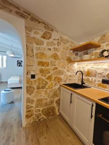 a kitchen with a stone wall and a sink at Paxos Dream House in Vlachopoulátika