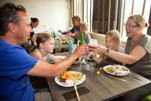 a group of people sitting at a table eating food at Mobilheim Budget 6p auf dem Campingplatz Scheldeoord in Baarland