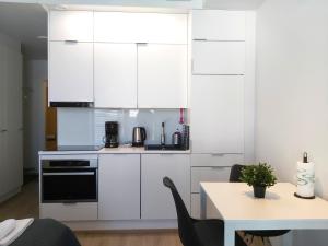 a kitchen with white cabinets and a table at Kotimaailma Apartments - keskustayksiö - Aleksanterinkatu in Tampere