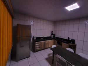 a kitchen with a refrigerator and a table and chairs at Casa aconchegante com hidro in Parauapebas