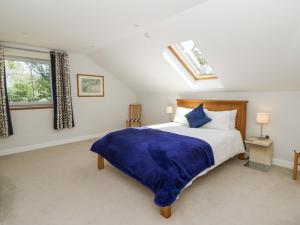 a bedroom with a large bed with a blue blanket at Little Penrhosgoch Barn in Llandrindod Wells