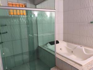 La salle de bains est pourvue d'une douche en verre et d'une baignoire. dans l'établissement Casa aconchegante com hidro, à Parauapebas 4 autres photos