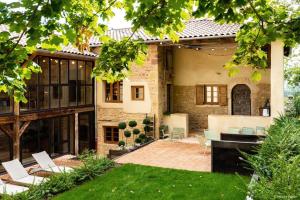a house with a patio with white chairs and a yard at Country Villa With Indoor Pool In Beaujolais in Romanèche-Thorins