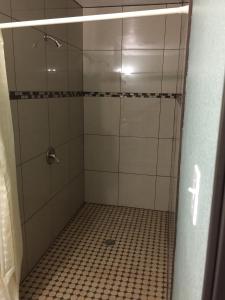 ducha con puerta de cristal y suelo de baldosa en Park Motel en Los Ángeles