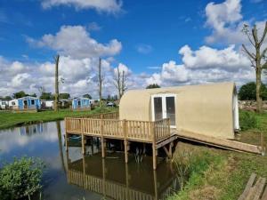 a house with a deck on a body of water at Camping Le Romantic in Steenvoorde