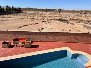 a swimming pool with chairs and a table and a beach at Dar Said Marrakech in Lalla Takerkoust