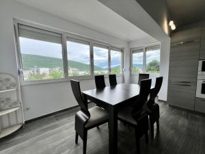 a dining room with a table and chairs and windows at Kumbor summer holiday in Topla +2 photos