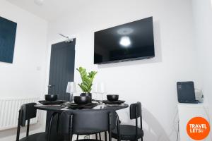 Una mesa negra con sillas negras y un televisor en la pared. en Brooke Park House, en Londonderry County Borough