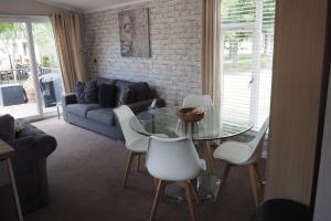 a living room with a glass table and white chairs at Wentworth Lodge in Tydd Saint Giles +6 photos