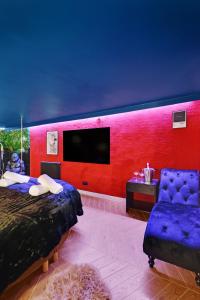 una camera da letto con una parete rossa, un letto e una sedia di Secret Love Room a Boulogne-Billancourt