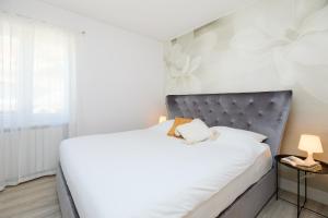 a bedroom with a white bed with a gray headboard at Hedera Estate Hedera A54 in Mlini