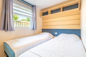 two beds in a bedroom with a window at Camping à 300m de la plage La Pege in Saint-Hilaire-de-Riez
