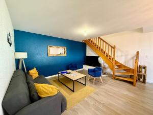 a living room with a couch and a blue wall at L'Appart des Copains, beau duplex & centre-ville in Gérardmer