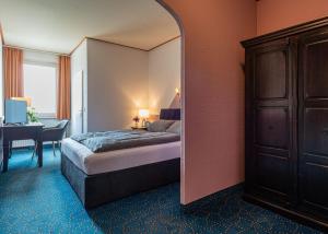 a bedroom with a bed and a desk and a mirror at Hotel Sternenlicht in Löhne