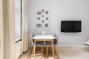 a dining room with a table and chairs and a tv at Good Weather Apartment in Poznań