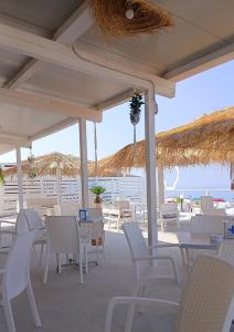 ein Restaurant mit weißen Stühlen und Tischen und dem Meer in der Unterkunft Hotel Le Mimose in Acquappesa