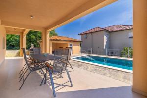 a patio with a table and chairs next to a swimming pool at Villa NOOK in Risika