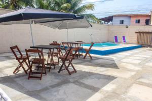 une table et des chaises avec un parasol à côté d'une piscine dans l'établissement Pousada Areias do Mutá, à Porto Seguro