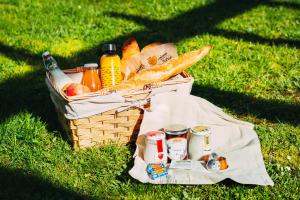 a picnic basket with bread and drinks on the grass at Résidence Prestige Odalys Le Domaine des Pins in Noirmoutier-en-l'lle