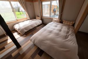 two beds in a room with two windows at ふらのの丘 in Kami-furano