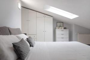 a bedroom with a white bed and a white dresser at Mansarda Massimo - Verbania Intra in Verbania