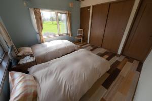 two beds in a small room with a window at ふらのの丘 in Kami-furano
