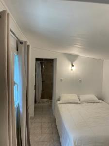 une chambre blanche avec un lit et une salle de bain dans l'établissement Deux mini villas distancees 10 metres pour 6 personnes, à Saint-Florent