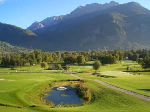 a golf course with a pond and mountains in the background at Joli logement au calme in Vésonne +12 photos