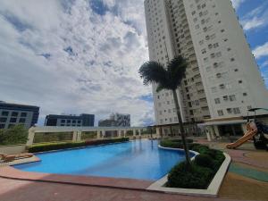a large swimming pool with a palm tree in front of a building at Studio Condo Unit with Balcony Avida IT Park in Cebu City