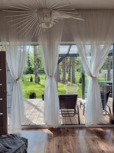 KlapkalnciemsJūras māja的带白色窗帘的卧室和露台