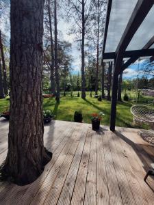 a wooden deck next to a tree with flowers at Jūras māja in Klapkalnciems +7 photos