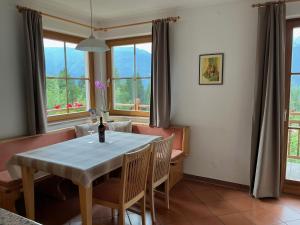 a dining room with a table and chairs and windows at Landhaus Mitsche in Hermagor